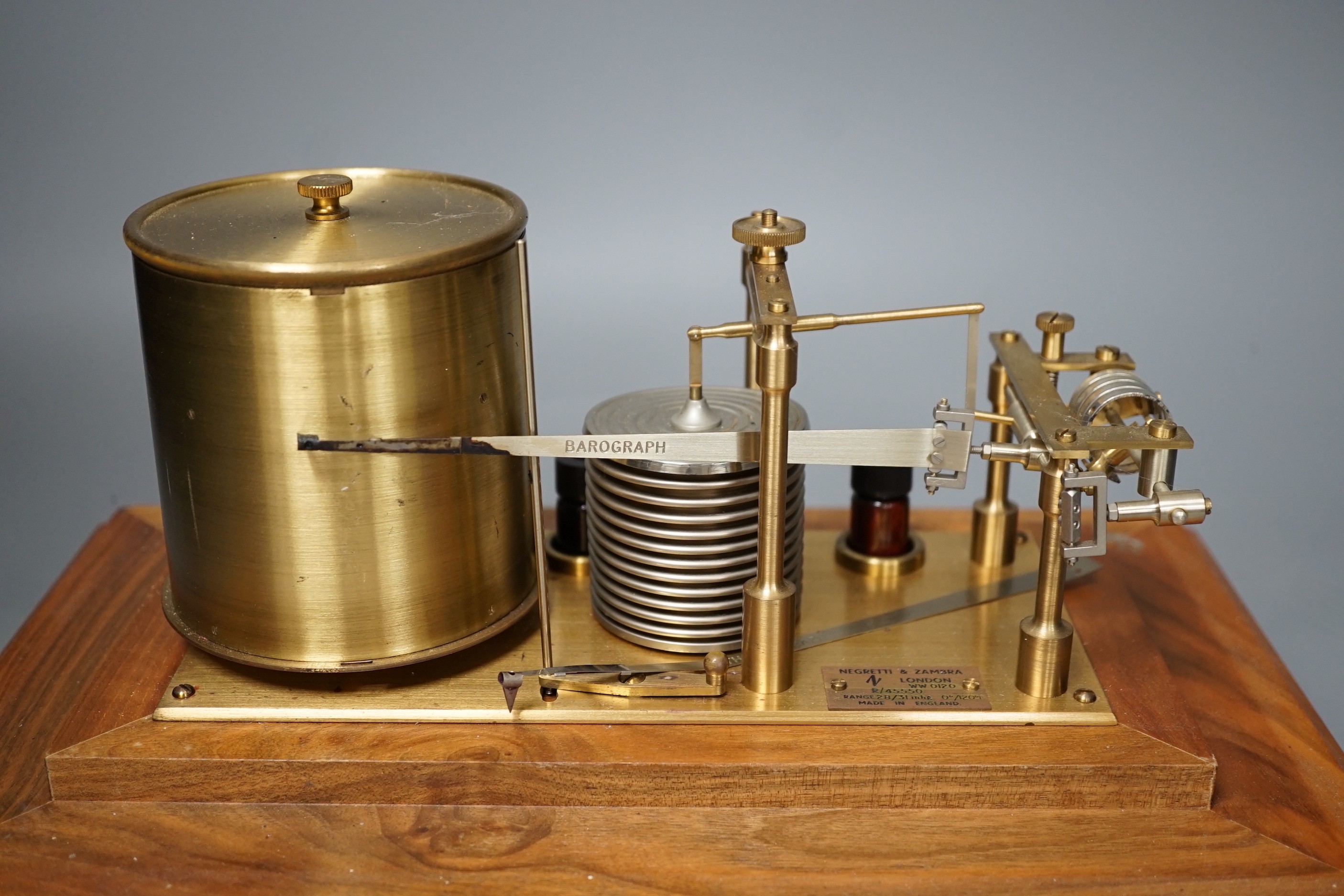 A Negretti & Zambra teak barograph with spare graph paper in case draw. 36cm wide.